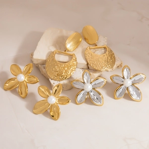 Two-tone pearl sunflower earrings and hammered gold geometric dangles on stone