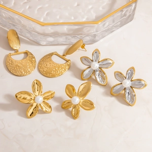 Three pairs of 18K gold plated mixed metal flower earrings with pearls on stone background