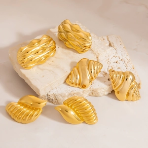 Golden sea shell stud earrings in organic spiral design on travertine stone