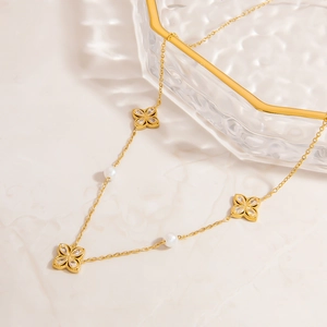 Detail van 18K vergulde klaverhangers met zirkonia en witte parels aan de ketting