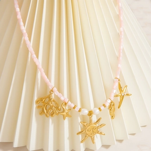 Close-up of pink beaded sun necklace with gold sea life charms and pearl accents