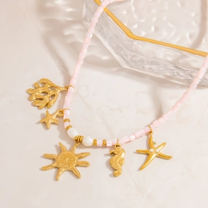 Detail of pink natural stone necklace with gold sun, seahorse and starfish charms