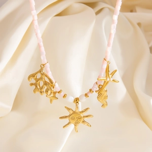Detailed view of pink stone beaded necklace with gold sea horse and sun face pendants