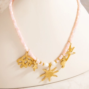 Pink stone beaded necklace with sun and starfish charms on a white display stand