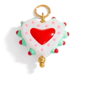 Macro detail of a colorful handmade heart pendant with pink dots and golden bead accents
