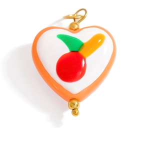 Close-up of heart charm with cherry motif and golden metal ring connector on white