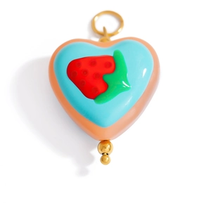 Macro shot of a heart-shaped summer pendant with strawberry pattern and gold accents