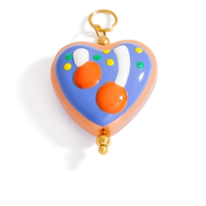 Macro shot of heart-shaped blue enamel pendant with orange cherry pattern and gold loop