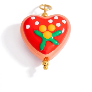 Detailed macro view of heart-shaped enamel charm with colorful polka dots and gold beads