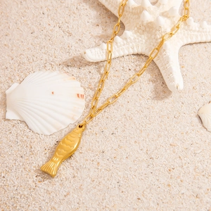 Goldene Fisch-Halskette auf Sand mit Seesternen und Muscheln im schlichten Ozean-Stil