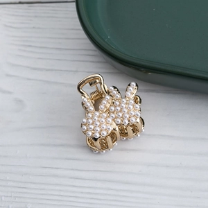 Pince à cheveux lapin dorée élégante avec perles blanches sur un fond en bois minimaliste