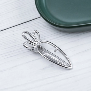 Macro shot of silver alloy carrot-shaped hollow hair clip on a white wooden background
