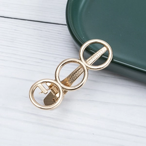 Elegant gold alloy hair clip with three hollow geometric rings on a white wood surface