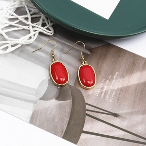 Detailaufnahme roter ovaler Marmorohrringe mit goldenem Haken und schlichtem Metallrahmen