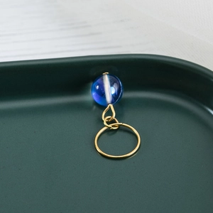 Detail of gold dreadlock bead featuring a blue translucent stone with white swirls