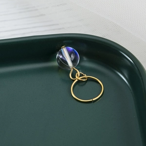 Macro view of a gold spiral ring accessory with an iridescent blue-purple aurora bead charm