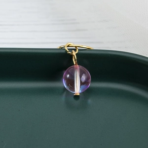 Detail of purple iridescent bead charm with gold ring for dreadlocks and DIY jewelry
