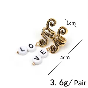 Golden spiral hoop earrings with white LOVE letter beads in a retro ethnic design