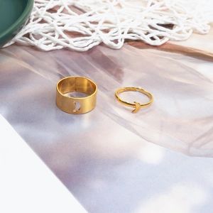 Adjustable gold crescent moon couple ring set on a magazine background