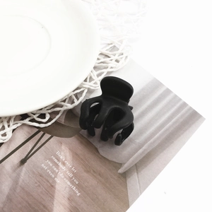 Detailaufnahme der mini Haarklammer in Schwarz Matt auf dekorativem Magazin Hintergrund