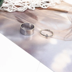 Close-up of silver lightning bolt cutout rings set on a decorative textured background