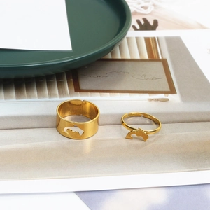 Detail of adjustable gold dolphin rings with hollow out design on a green tray