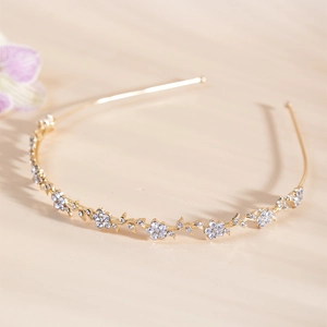 Close-up of golden alloy headband with delicate rhinestone flowers and vine leaves