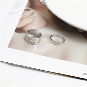 Close-up of adjustable silver airplane couple rings with heart cutout on a magazine