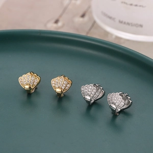 Elegant gold and silver shell earrings with micro-set cubic zirconia in a decorative tray