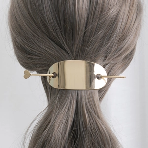 Détail d'une épingle à cheveux cœur dorée et pince ovale en métal poli