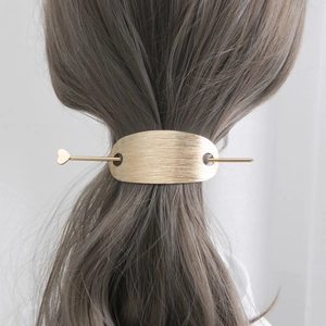 Élégant pic à cheveux doré avec breloque cœur et clip ovale mat sur une queue de cheval