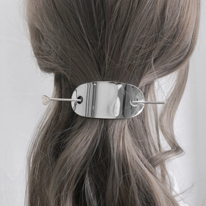 Épingle à cheveux en métal argenté poli sur cheveux bruns avec plaque ovale minimaliste