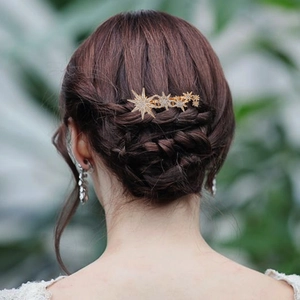 Elegant gold hair comb with rhinestone stars worn in a delicate braided hairstyle