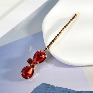 Barrette dorée élégante avec des strass rouges en forme de larme et des accents brillants