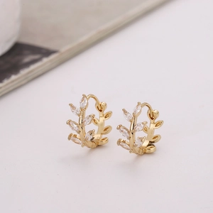 Close-up of gold hoop earrings featuring leaf designs and marquise-cut zircon stones