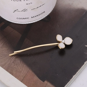 Barrette dorée élégante avec fleur blanche et cristal sur fond de magazine