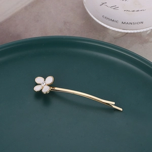 Barrette dorée élégante avec fleur blanche et cristal sur un fond vert foncé