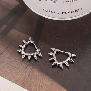 Silver punk heart earrings with rivets and micro zircon on dark magazine background