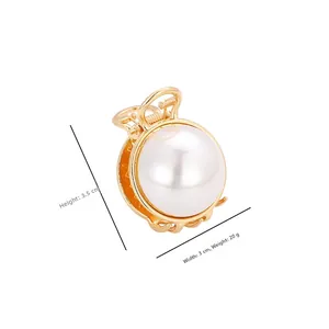 Détail d'une mini pince à cheveux dorée avec perle blanche, hauteur de 3,5 cm