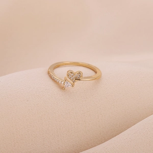 Golden heart-shaped zircon ring with arrow design on elegant pink silk background