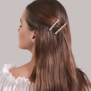 Détail de barrettes élégantes en or rose avec strass brillants portées sur cheveux