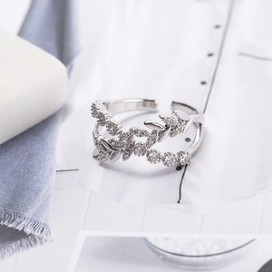 Elegant silver zircon leaf crisscross open ring on a luxury marble tray display