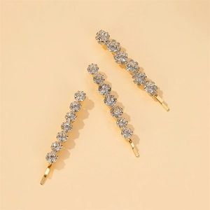 Détail d'un ensemble de trois barrettes dorées serties de strass blancs scintillants