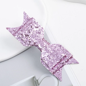 Detailed macro view of a pink glitter bow accessory on a clean minimalist white plate