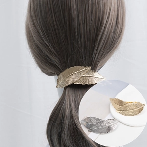Macro view of vintage gold and silver leaf hair clips showing detailed metallic vein textures