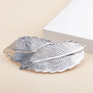 Elegant vintage silver leaf spring hair clip with realistic vein texture on beige background