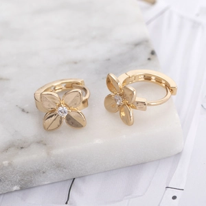 Elegant gold flower hoop earrings for women with sparkling zircon stone on marble surface