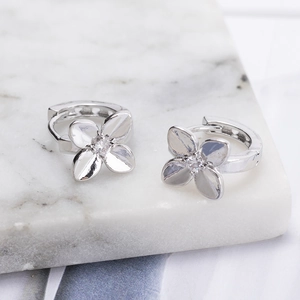 Minimalist silver flower hoop earrings with zircon stones on marble display stand