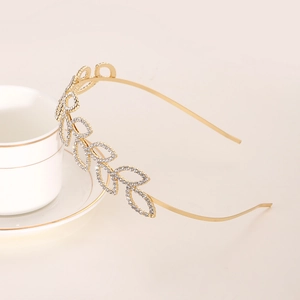 Elegant gold leaf headband with sparkling rhinestones on a stylish white ceramic coffee cup