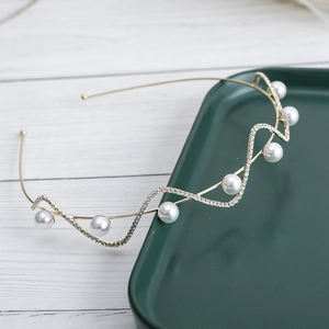 Elegant wave-shaped gold headband with sparkling rhinestones and white faux pearls